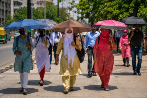 भारत में भीषण गर्मी के दौरान धूप से बचने के लिए छाता इस्तेमाल करते लोग