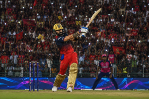 IPL मैच के दौरान विराट कोहली स्टेडियम में शानदार शॉट लगाते हुए, जबकि हजारों फैंस उनका उत्साह बढ़ाते नजर आ रहे हैं।
