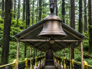 तारकेश्वर महादेव मंदिर के मार्ग पर लटका विशाल घंटा और देवदार के घने जंगलों के बीच बना शांत पैदल मार्ग